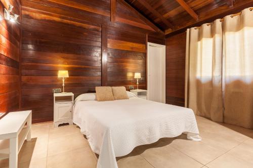 Wood House Massaranduba في كوبيليس: غرفة نوم بجدران خشبية وسرير بملاءات بيضاء