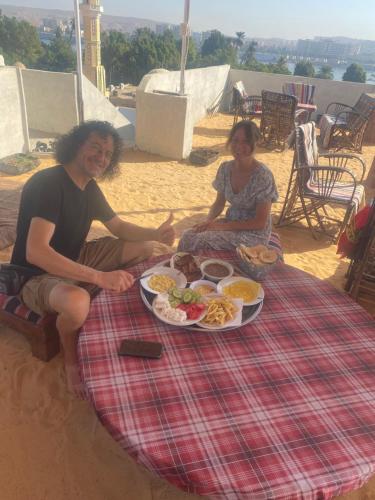 mężczyzna i kobieta siedzący przy stole z talerzem jedzenia w obiekcie Nuba Heart w mieście Aswan