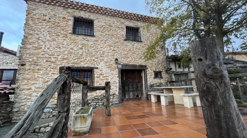 um antigo edifício de pedra com um portão de madeira e uma árvore em Casa Rural Negua en La Cuenca, Soria em La Cuenca