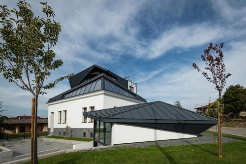 un bâtiment blanc avec un toit noir et un arbre dans l'établissement LANTerna Boutique Hotel, à Srbac