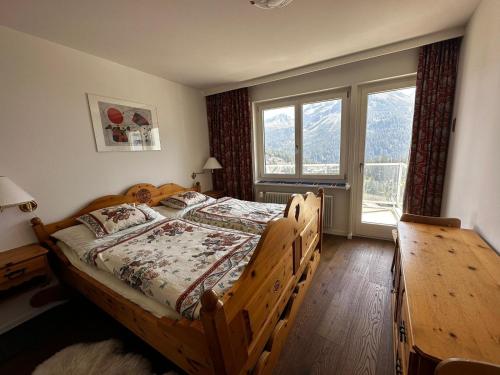 a bedroom with a wooden bed and a large window at Ritschis Home in Arosa