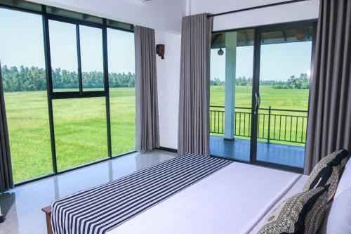 a room with large windows and a bed and chairs at Oragan Resort in Tissamaharama