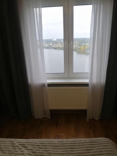 a bedroom with a window with a view of a river at Revutskogo 54 метро Харьковская, Позняки, Квартира з видом на озеро in Kyiv