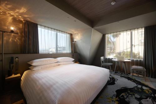 a bedroom with a large bed with white sheets and windows at THE HOTEL HIGASHIYAMA by Kyoto Tokyu Hotel in Kyoto