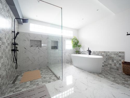een badkamer met een bad en een glazen douche bij Grand Penthouse by Grand Orlov Hotel in Patong Beach