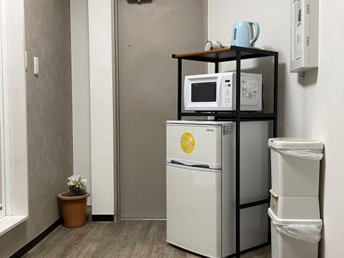 a microwave on top of a refrigerator next to a shelf at TokyoGuest Akihabara in Tokyo