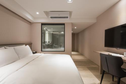 a bedroom with a bed and a desk and a tv at Spring Rhapsody Hotel in Taichung