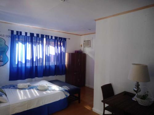 a bedroom with a bed and a blue window at Malapascua Beach and Dive Resort in Logon