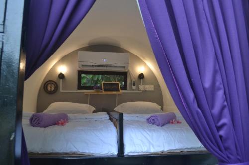 2 Betten in einem Zimmer mit lila Vorhängen in der Unterkunft Bagan Pinang Guest House in Port Dickson