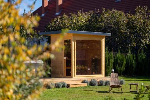 a cabin with a glass door in a garden at NaturART Vendégház Tiszafüred in Tiszafüred