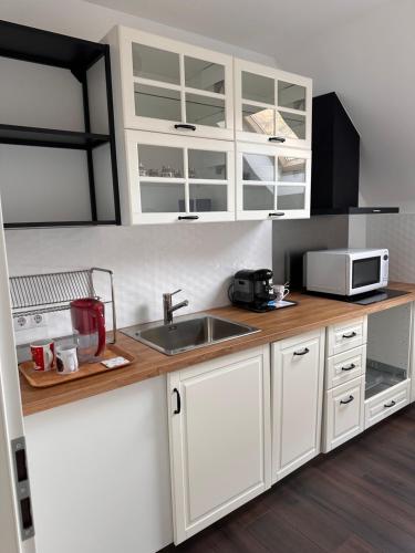 a kitchen with white cabinets and a sink and a microwave at Forest Lux in TÄƒuÅ£ii MÄƒgheruÅŸ