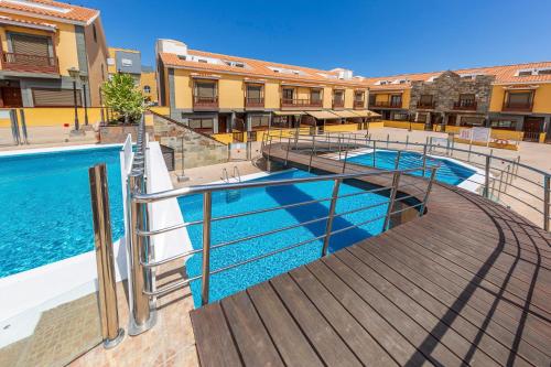 una piscina con terrazza in legno accanto a un edificio di MEDANO4YOU The Guachinche House a El Médano