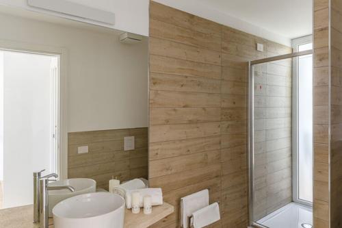 een badkamer met 2 wastafels, een bad en een douche bij Residence Capo Falcone Stintino in Stintino