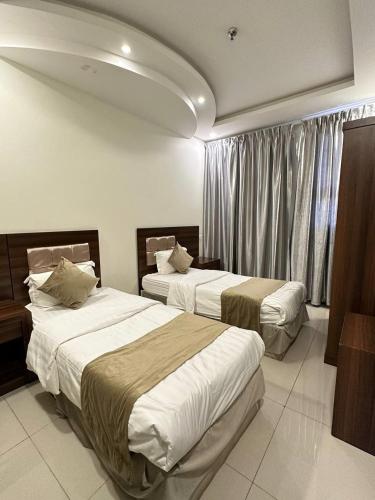 ein Hotelzimmer mit 2 Betten und einem Fenster in der Unterkunft Lilas Taif in Ta'if