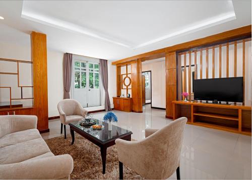a living room with a table and chairs and a television at Petro House Vung Tau - Block B in Vung Tau