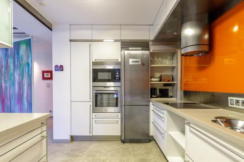 cocina con armarios de color naranja y blanco y nevera en Apartamentos Tribuna, en Málaga