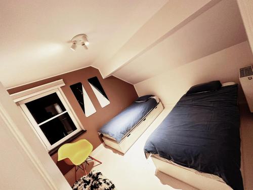 1 dormitorio con 1 cama y 1 silla amarilla en Le mazot d’Edouard et Celestin en Profondeville