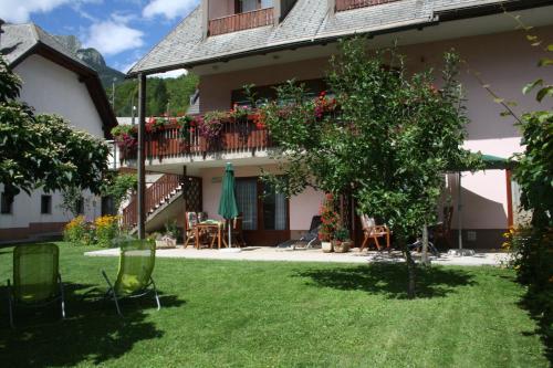 a house with a yard with chairs and a tree at Apartments Kravanja in Bovec
