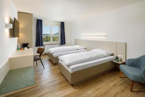 une chambre d'hôtel avec deux lits et une chaise dans l'établissement Hotel an der Reuss, à Gisikon