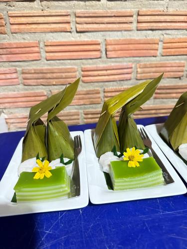 dos platos de comida con flores amarillas. en Ban Suweena, en Uthai Thani