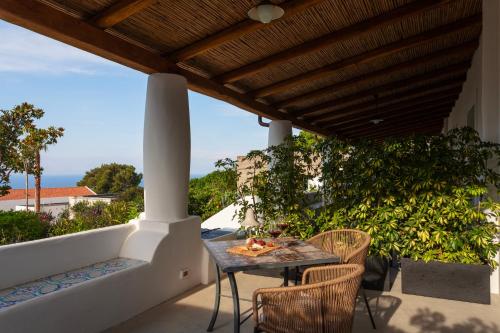 a patio with a table and chairs under a wooden roof at Frangimare - La Malandrina in Malfa