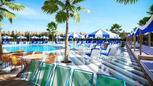 a resort pool with chairs and tables and palm trees at tent Mojito Suites in Magaluf