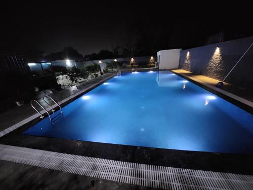 a large swimming pool with blue lighting at night at The Lagoon in Samālkha