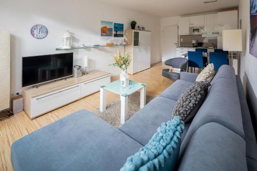 a living room with a blue couch and a tv at Haus Inselkieker Wohnung 1 in Norderney