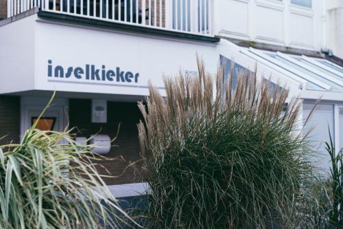 a sign on the side of a building with plants at Haus Inselkieker Wohnung 3 in Norderney