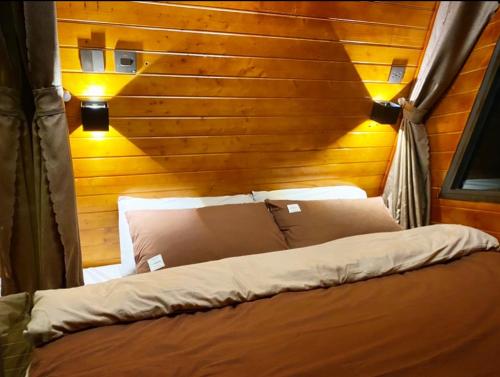a bed in a room with a wooden wall at Nhà Yên 's 2 Bedrooms Lake Resort Hotel Homestay in Pleiku