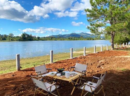 a wooden table and chairs next to a lake at Nhà Yên 's 2 Bedrooms Lake Resort Hotel Homestay in Pleiku