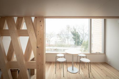 a room with a table and three stools in front of a window at Teshima ESPOIR PARK in Ieura