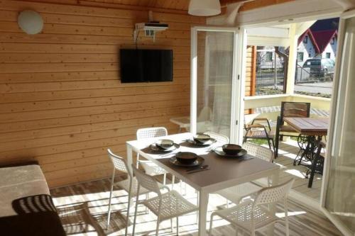 a white table and chairs on a porch with a television at Cottage for 4 people Ustronie Morskie in Ustronie Morskie