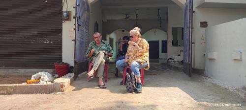 grupa ludzi siedzących na krzesłach przed budynkiem w obiekcie Khajurāho Hostel w mieście Khajuraho