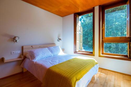 a bedroom with a bed and two windows at La Panera de Pucho in Pontevedra