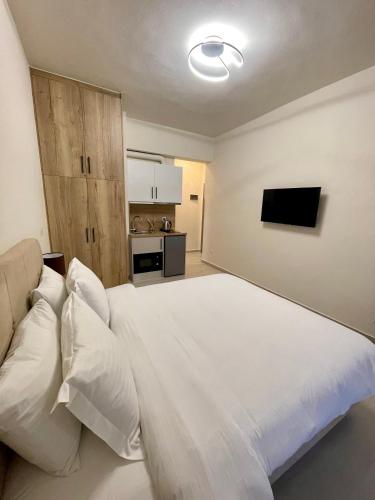 a bedroom with a white bed and a kitchen at Lemnos Urban Escape in Mirina
