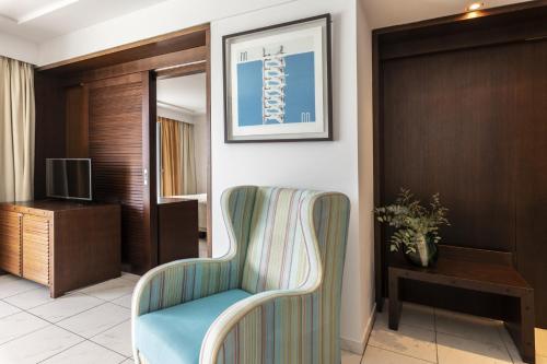 a hotel room with a chair and a television at Louis Apostolata Island Resort in Skala Kefalonias
