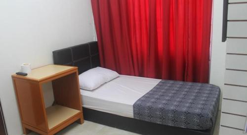 a small bedroom with a bed with a red curtain at Meera Heritage Motel in George Town