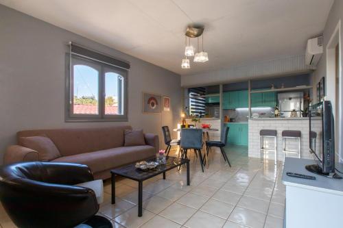 a living room with a couch and a table and a kitchen at Ikaros Lodge in Agia Pelagia