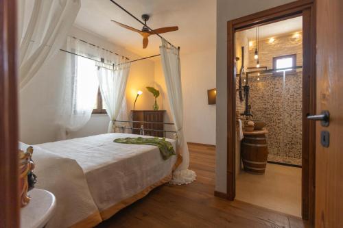 a bedroom with a bed with a ceiling fan and a bathroom at VILLA I MORI 4, Emma Villas in Rosolini