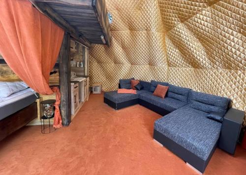a living room with a blue couch and a bed at Glamping Jedlova - Romantic and family getaway in Horní Podluží