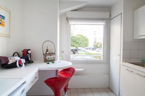 een witte keuken met een rode stoel en een raam bij Le Léon Ungemach - Studio à Schiltigheim in Schiltigheim