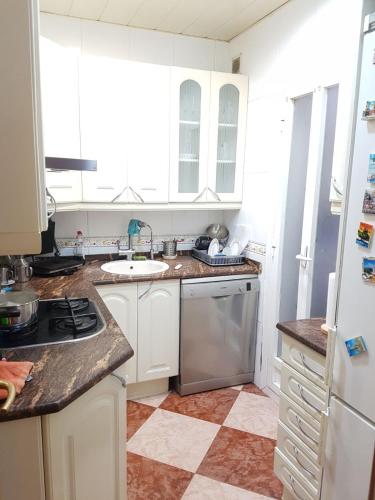 eine Küche mit weißen Schränken und einem Waschbecken in der Unterkunft Habitacion Acogedora en piso compartido cerca del Camp Nou in Hospitalet de Llobregat