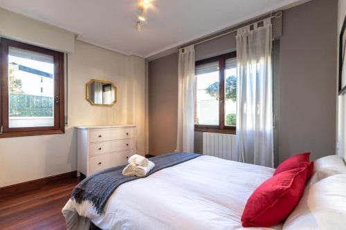 Espectacular apto con terraza en Sopela في سوبيلانا: غرفة نوم مع سرير أبيض كبير مع وسائد حمراء