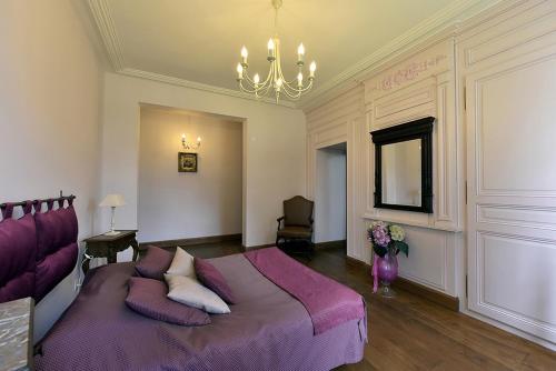 a bedroom with a large purple bed with pillows at Les Gîtes du Domaine de la Traxène in Coupelle-Vieille