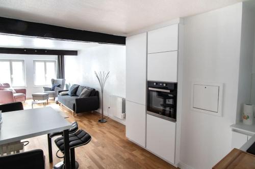 d'une cuisine et d'un salon avec des placards blancs et une table. dans l'établissement Le Gutenberg - Joli T2 dans le Carré d'Or, à Strasbourg