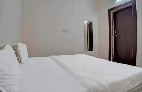 a bedroom with a white bed and a wooden door at New Narayan Palace in Bhopal