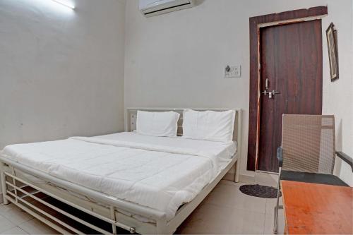 a white bed in a room with a wooden door at New Narayan Palace in Bhopal