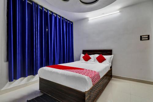 a bed with red pillows in a room with blue curtains at Seshadri Homestay in Tirupati