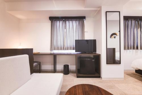 Cette chambre comprend un bureau, une télévision et un lit. dans l'établissement WAYFARER Matsu, à Osaka
